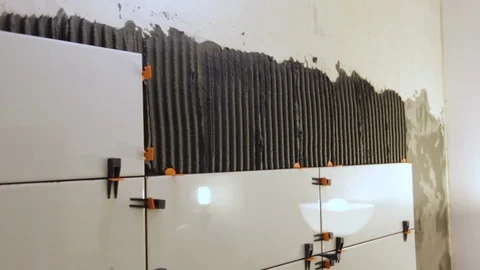 Worker laying tiles on the wall 库存影片 128413196