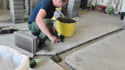 Worker lays blocks on the floor for construction project in building site Stock Footage 332132667