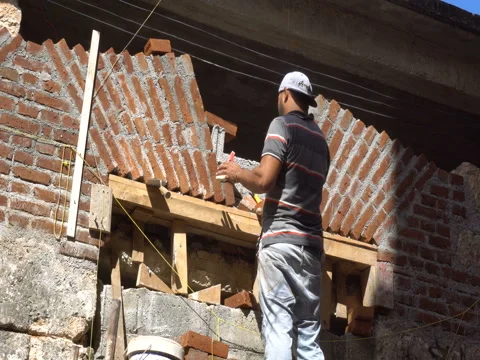 Worker lays bricks and smears the wall by cement at a construction Stock Footage 71056877