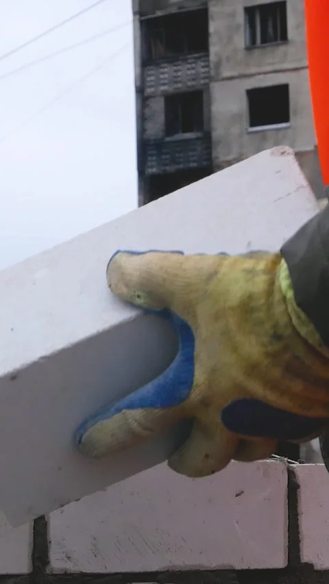 A worker lays bricks on cement, builds the wall of the house Stock Footage 311976021
