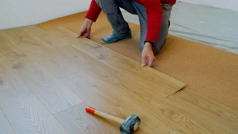 A worker lays down the laminate flooring on the cork floor. Repair of the Stock Footage 154848300