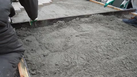 A worker lays down sand for paving slabs. Construction Video stock 330343074