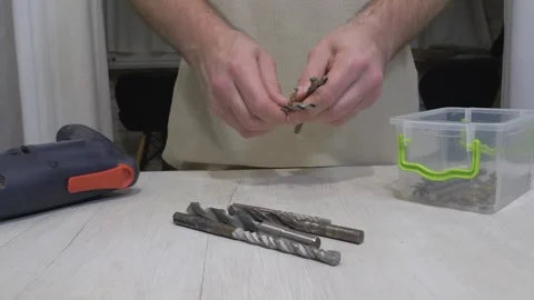 A worker lays out drills on a workbench. An electric drill and metal drill bits Stock Footage 336466329