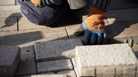 A worker lays paving slabs. The builder knocks with a rubber hammer. Stock Footage 232204481