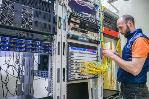 Worker lays telecommunication cables in the server room. A man twists the wir 库存照片