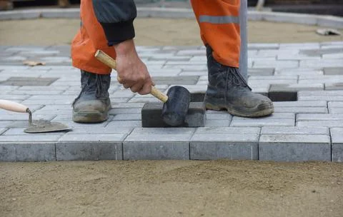 The worker lays the tile in even rows. Stock Photos