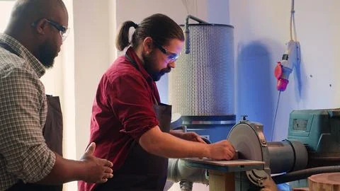 Worker learning from woodworking professional how to use grinding machine Stock Photos