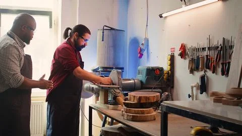 Worker learning from woodworking professional how to use grinding machine Stock Photos