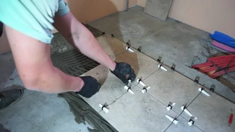 A worker is leveling the ceramic tile with wedges and clips. Video stock 150962913
