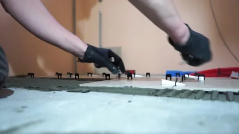A worker is leveling the ceramic tile with wedges and clips. Video stock 150962920