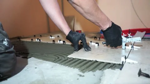 A worker is leveling the ceramic tile with wedges and clips. Video stock 150963039
