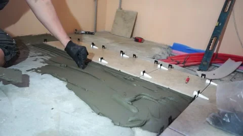A worker is leveling the ceramic tile with wedges and clips. Video stock 152241456