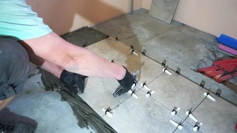 A worker is leveling the ceramic tile with wedges and clips. Video stock 152241501