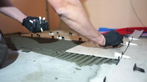 A worker is leveling the ceramic tile with wedges and clips. Video stock 152241677