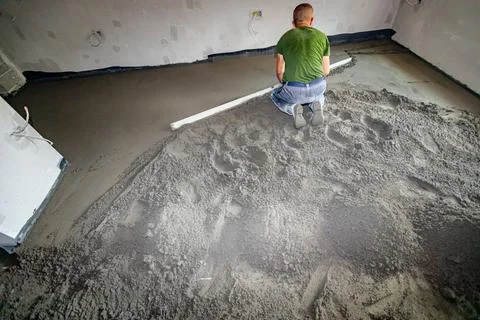Worker is leveling floor screed over floor heating system in residential bu.. Stock Photos