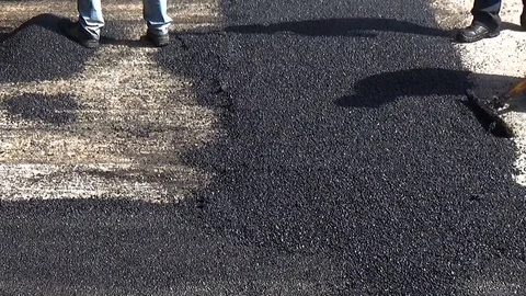 Worker leveling fresh asphalt during asphalt pavement repair Stock-Footage 84590086