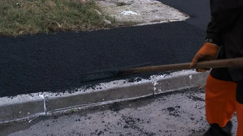 Worker Leveling Fresh Asphalt on a Road Construction Site. Worker Using Stock Footage 123876442
