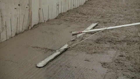Worker leveling wet concrete floor with tool at construction site Stock Footage 315957588