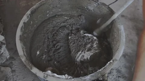 The worker levels the floor with a tool. The worker stands in fresh mortar, c Stock-Footage 145849642