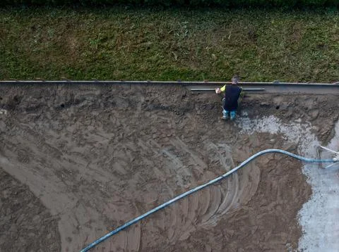 Worker Levels Sandy Surface with Tool Near Grass Strip Stock Photos