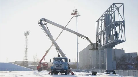 Worker in lift bucket during installation big billboard in bad weather. Workers Stock Footage 84742931