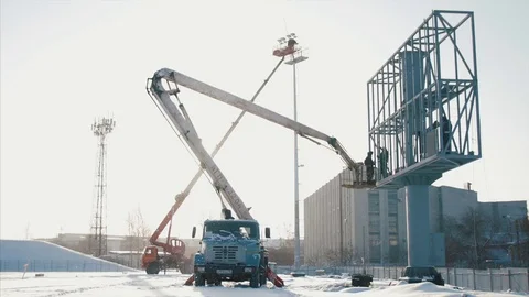 Worker in lift bucket during installation big billboard in bad weather. Workers Stock Footage 84742986