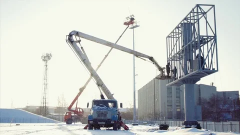 Worker in lift bucket during installation big billboard in bad weather. Workers Stock Footage 84743035