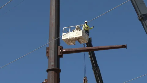 Worker is lifted to support bracket of gigantic telephone pole, 4K. Stock Footage 244491117