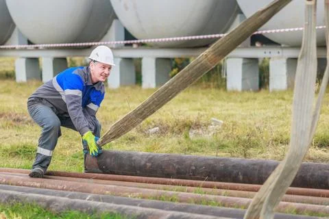 Worker Lifting Heavy Pipe at Construction Site Outdoors Stock-Fotos