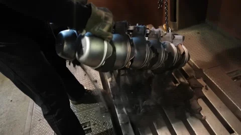 Worker lifting rack of cast iron pots with overhead chain hoist in foundry Видео 345029679