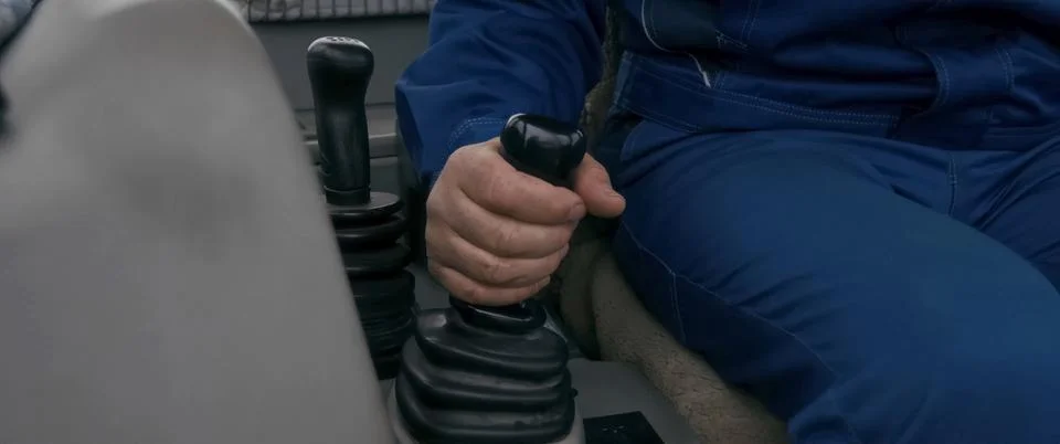 Worker on a loader holds the control lever with his hand Stock Photos