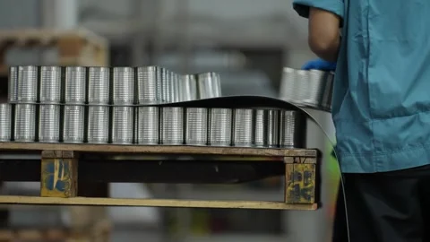 Worker loading cans onto an automated conveyor system Stock-Footage 330760262