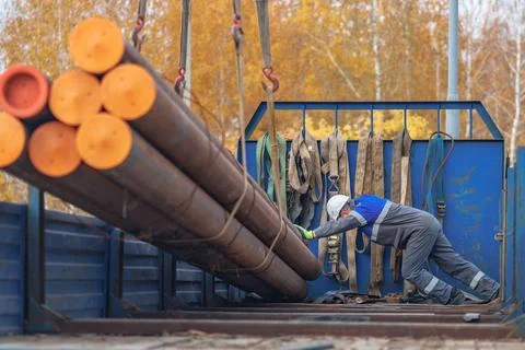 Worker Loading Steel Pipes at Construction Site in Autumn Stock Photos