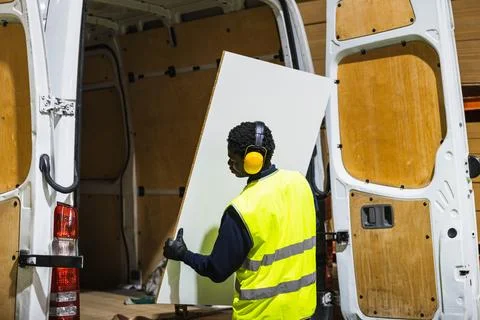 Worker loading white panel into delivery van Foto stock