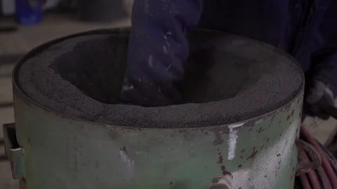 A worker loads black sand into equipment. Stock Footage 105228449