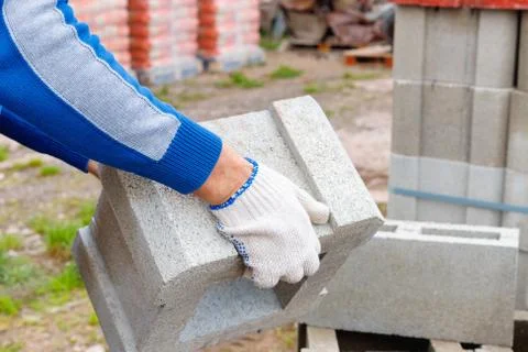 Worker loads cinder blocks  from cement slurry for construction Foto stock