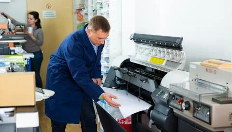 Worker loads new roll of paper into the plotter Foto stock