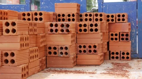 A worker loads red clay bricks into a small open truck bed, performing manual Stock Footage 312781172
