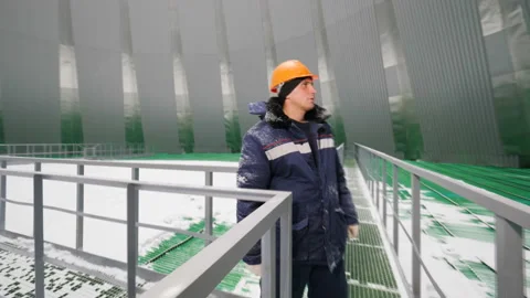 Worker looks around inside cooling tower under snowfall Stock Footage 94759612