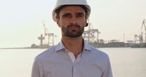 Worker looks into camera standing against port construction Video stock 166054785