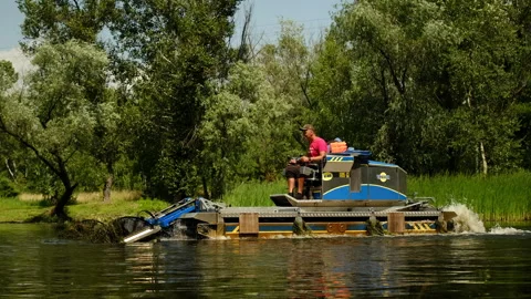 Worker on the machine cleans the water of the river from algae and trash Video stock 244992295