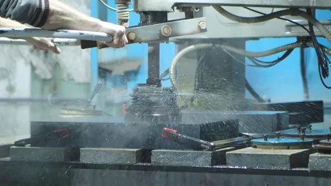 The worker at the machine grinds porcelain stoneware slabs to make porcelain Stockbeeldmateriaal 255634869