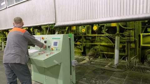 A worker maintains a paper machine. Paper production. Stockbeeldmateriaal 301464478