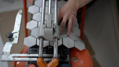 The worker makes a cut in the tile for the socket. The master cuts the tile.. Stock Photos