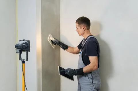 Worker makes final smoothing plaster on the wall. Stock Photos