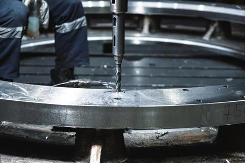 Worker makes hole in metal ring with radial drilling machine Stock Photos