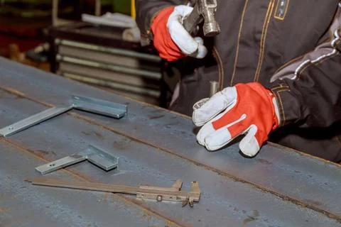 The worker makes a mark on a metal surface. Drilling holes in metal profiles  Stock Photos