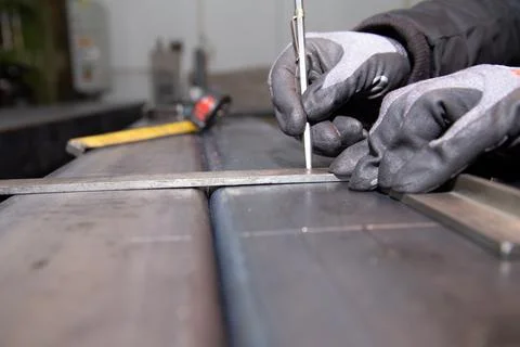 Worker makes a mark on metal surface. Drilling holes in metal profiles for Stock Photos