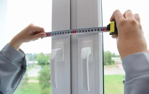 A worker makes a measurement of a closed plastic window. Stock Photos