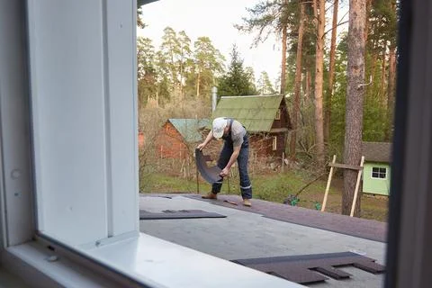 A worker makes a roof. View from the window Stock Photos